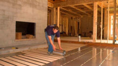 Man rolling out aluminum flooring material onto floor of new construction.