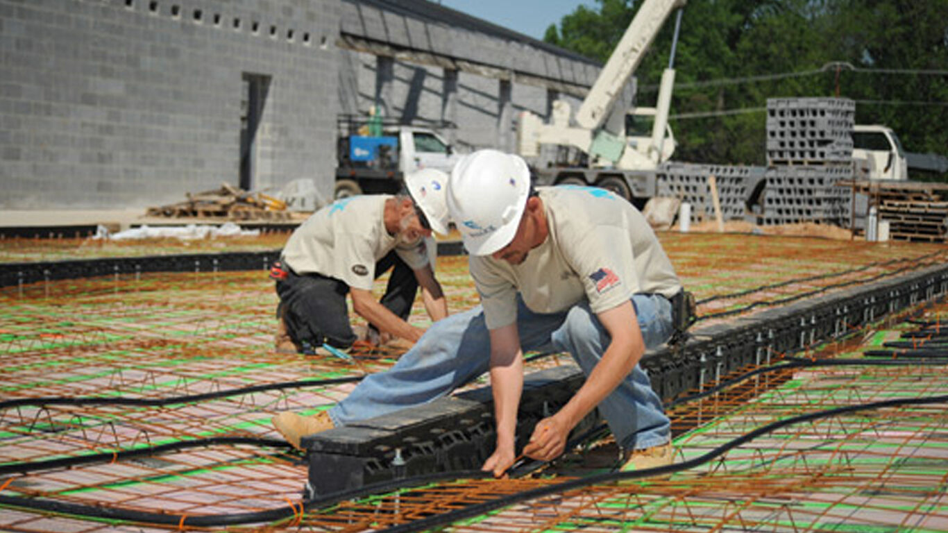 Men working on exterior foundation floor for fire department.